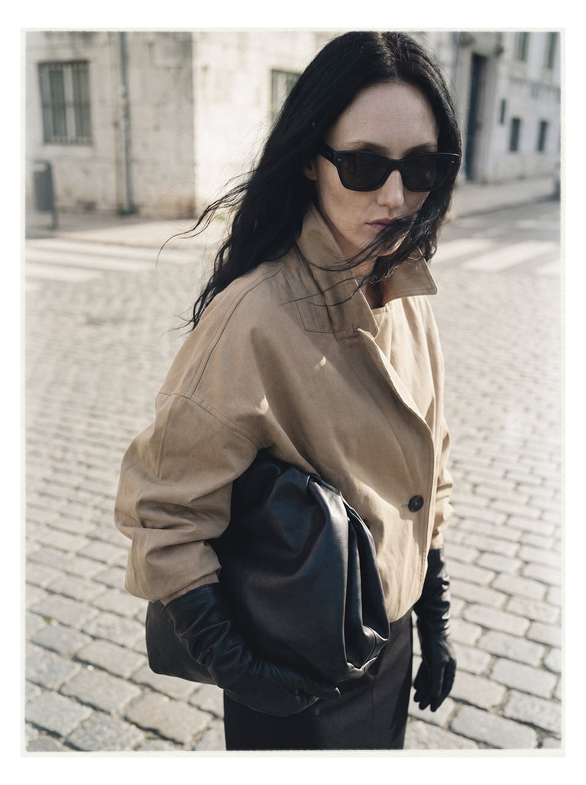 Street editorial: model in a beige trench beside a vintage car